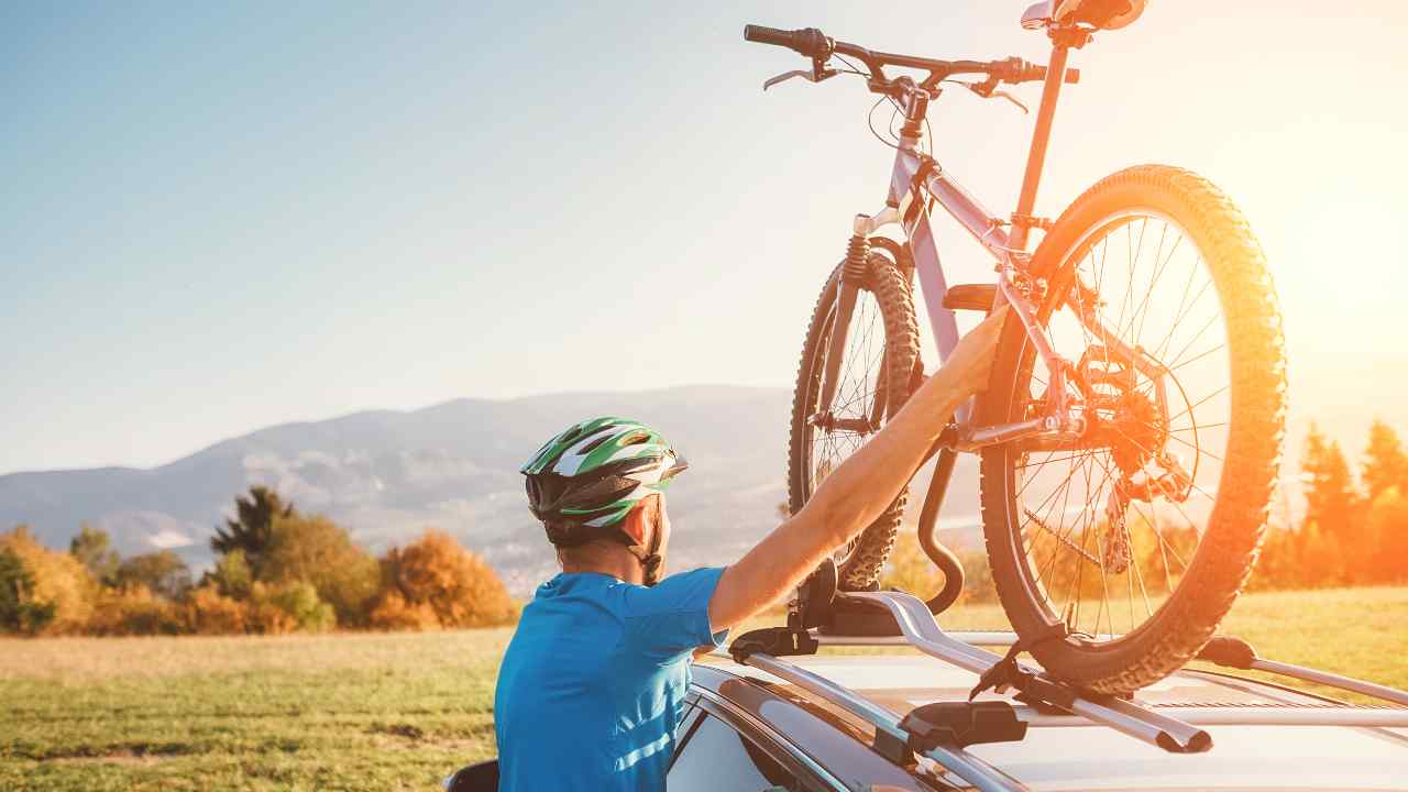 Un ciclista che monta la bici su un'auto - fonte stock.adobe - giornalemotori.it